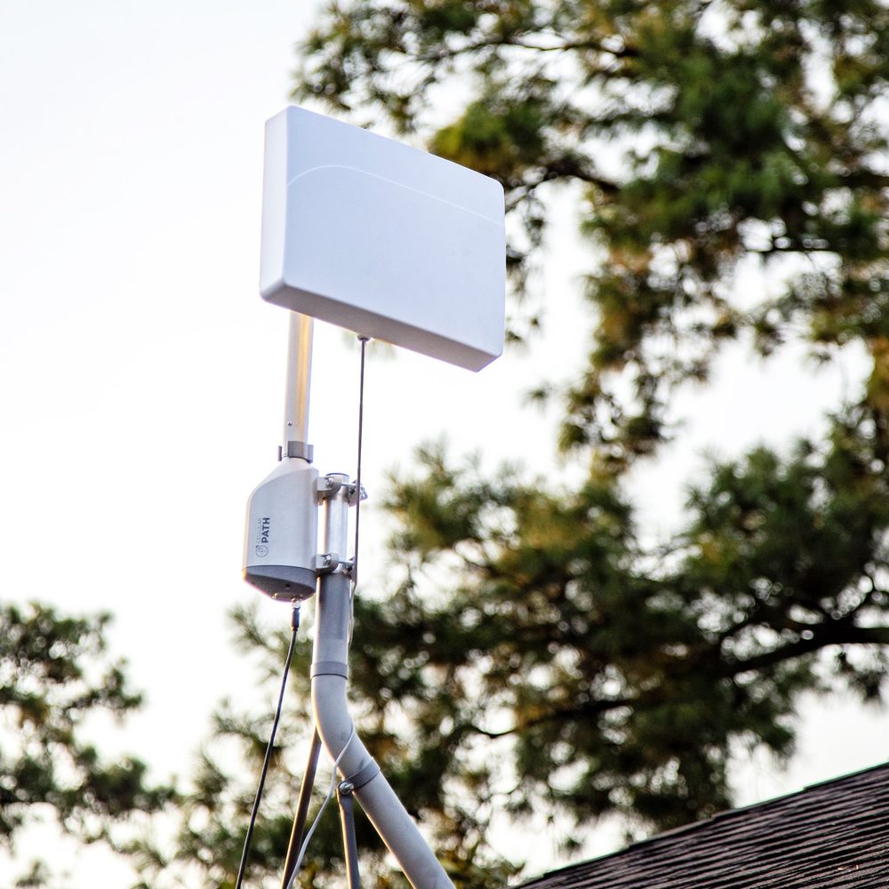 A SOCA rotator and a panel antenna on a braced mast standing above a roofline.