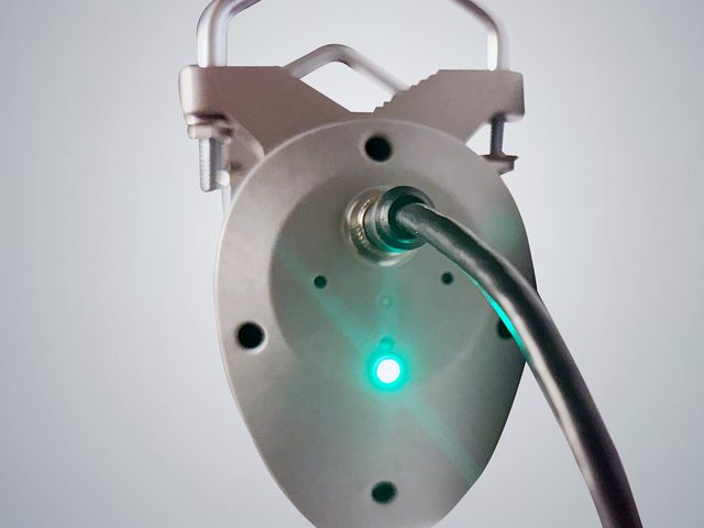 The underside of a SOCA rotator, showing the four pin M12 power and control connector and the lit power indicator.